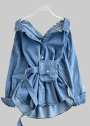 Blue denim jacket with a bow detail on a hanger against a decorative background.