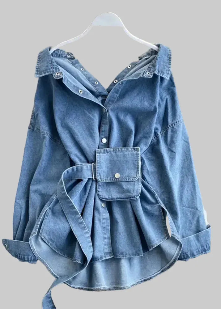 Blue denim jacket with a bow detail on a hanger against a decorative background.