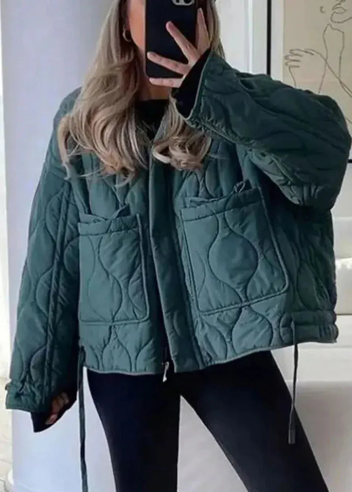 Person wearing a green quilted jacket indoors