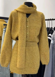 Mustard yellow knitted cardigan on a mannequin against a clothing rack background
